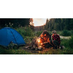 Father and son camping outdoors with a tent and campfire 